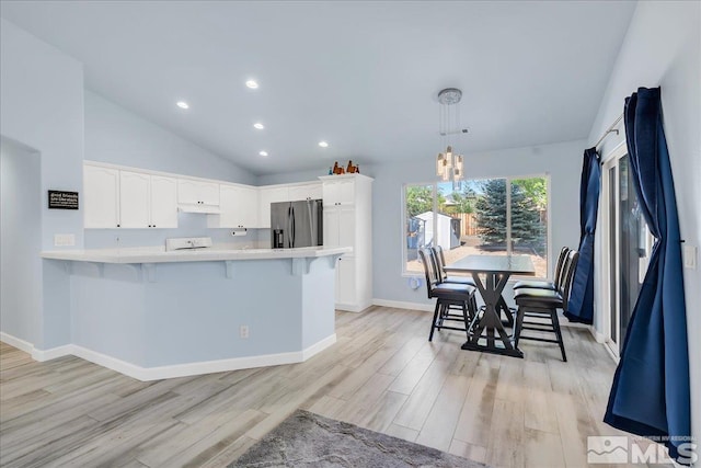 7766 Cerritos Cir, Sparks, NV 89436 - kitchen featuring stainless steel fridge, a peninsula, vaulted ceiling, light countertops, and a kitchen breakfast bar