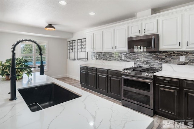 2160 Mammatus Dr, Sparks, NV 89441 - kitchen with stainless steel appliances, a sink, white cabinetry, dark cabinetry, and baseboards
