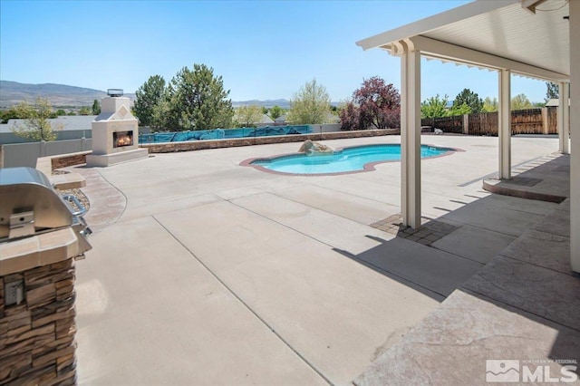 2160 Mammatus Dr, Sparks, NV 89441 - view of pool featuring a lit fireplace, a patio area, a mountain view, and a fenced backyard