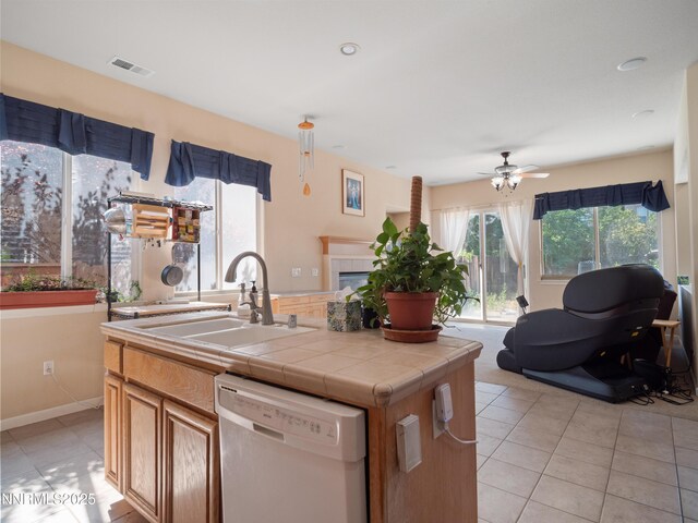 1840 Granite Chief Dr, Reno, NV 89521 - kitchen with white dishwasher, ceiling fan, light tile patterned floors, tile counters, and an island with sink