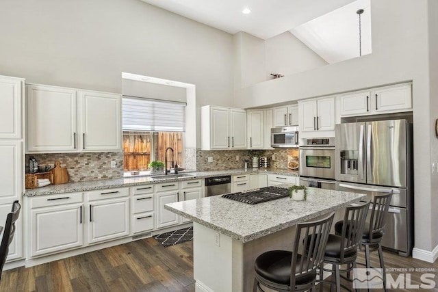 4822 Ramcreek Trl, Reno, NV 89519 - kitchen with stainless steel appliances, a sink, a towering ceiling, a center island, and dark wood-style floors