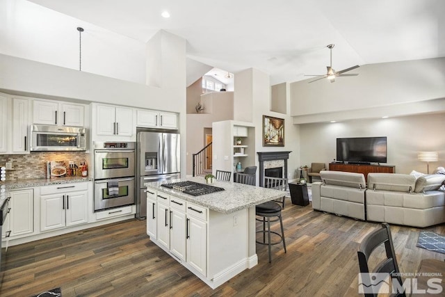 4822 Ramcreek Trl, Reno, NV 89519 - kitchen with appliances with stainless steel finishes, ceiling fan, a kitchen bar, white cabinetry, and light stone countertops