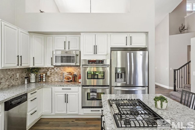 4822 Ramcreek Trl, Reno, NV 89519 - kitchen with stainless steel appliances, light stone countertops, tasteful backsplash, white cabinetry, and dark wood-style floors