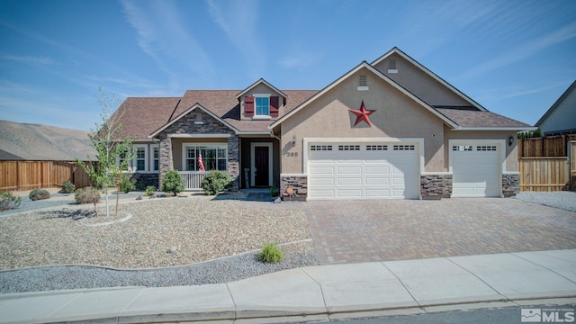craftsman inspired home featuring stone siding, stucco siding, fence, and a garage