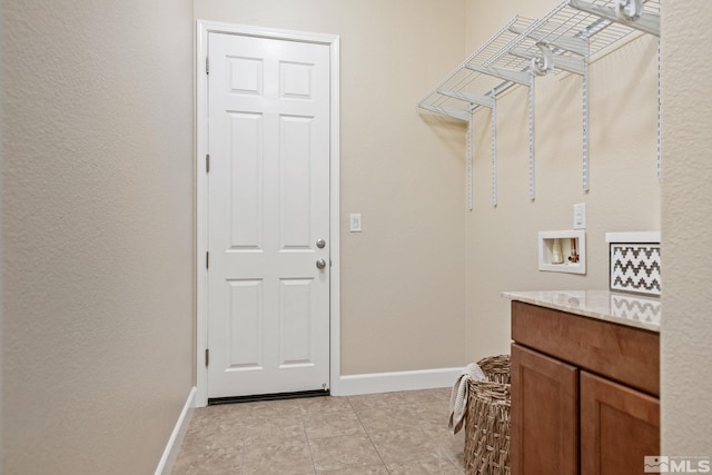 clothes washing area with hookup for a washing machine, baseboards, light tile patterned floors, and cabinet space