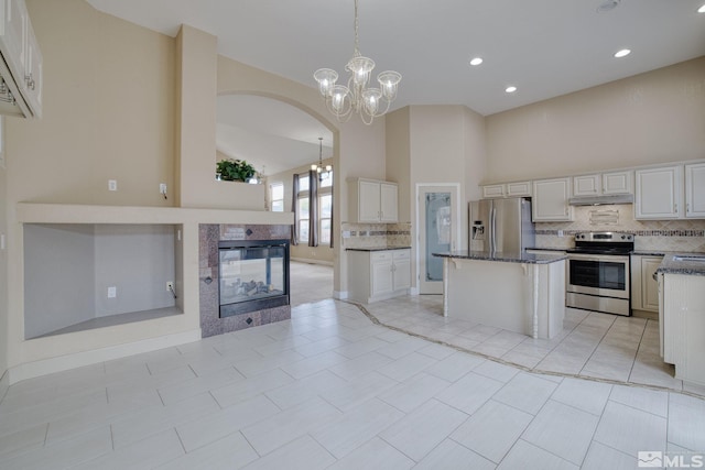 250 Corral Dr, Dayton, NV 89403 - kitchen featuring stainless steel appliances, backsplash, arched walkways, high vaulted ceiling, and dark stone counters