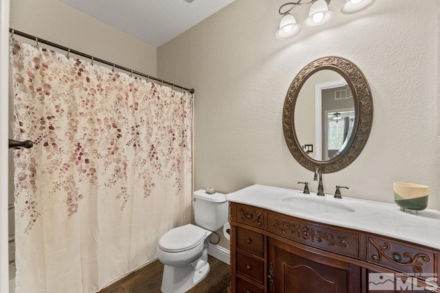 bathroom with wood finished floors, toilet, vanity, baseboards, and curtained shower