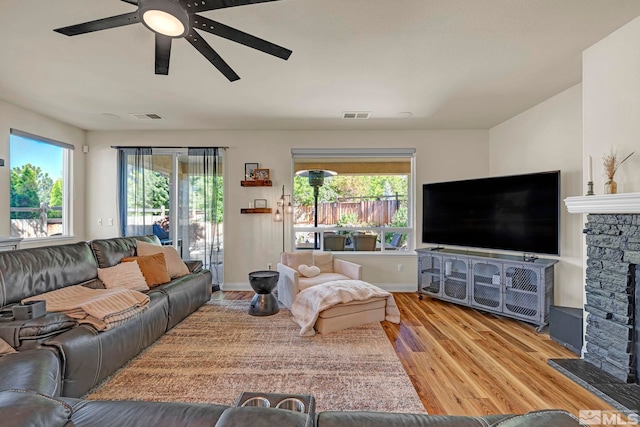 4184 Passage Dr, Sparks, NV 89436 - living room with wood finished floors, a stone fireplace, a ceiling fan, and plenty of natural light