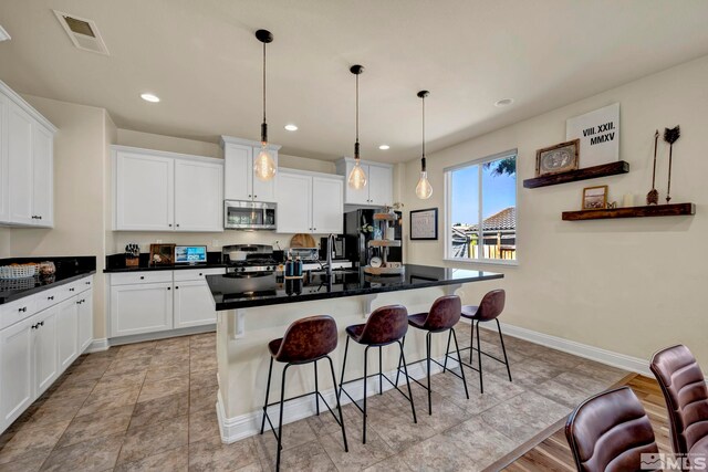 4184 Passage Dr, Sparks, NV 89436 - kitchen featuring stainless steel microwave, range with gas stovetop, white cabinets, a kitchen bar, and dark countertops