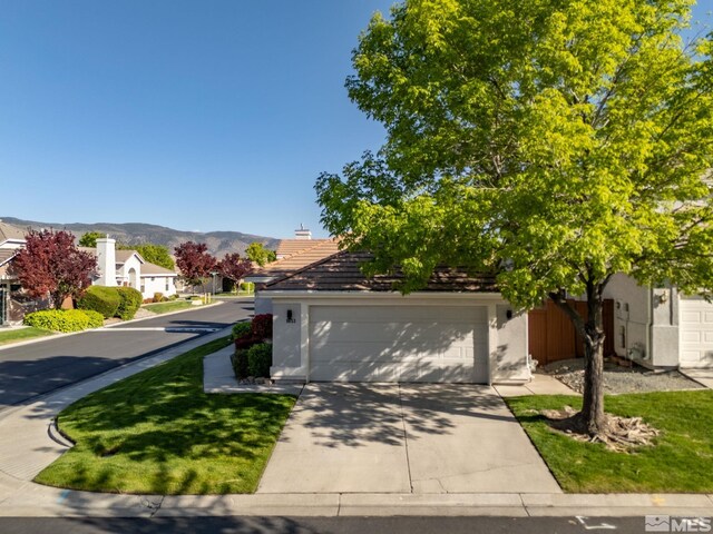 obstructed view of property featuring a mountain view, concrete driveway, stucco siding, a garage, and a tiled roof