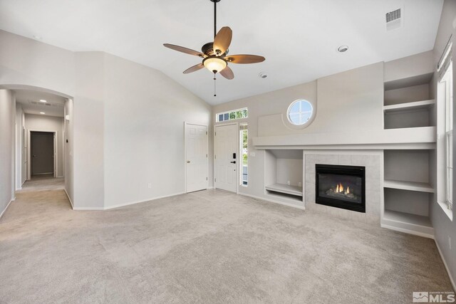 unfurnished living room featuring baseboards, carpet flooring, arched walkways, a ceiling fan, and built in features
