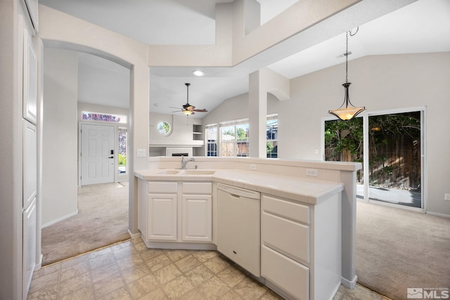 kitchen featuring white dishwasher, a sink, lofted ceiling, tile counters, and a fireplace