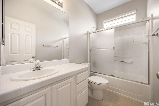 full bathroom with tile patterned flooring, vanity, toilet, and combined bath / shower with glass door