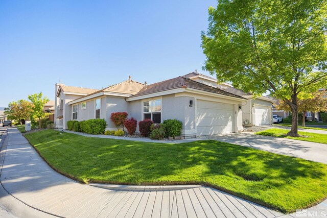 ranch-style house with a garage, stucco siding, a front lawn, and a tile roof