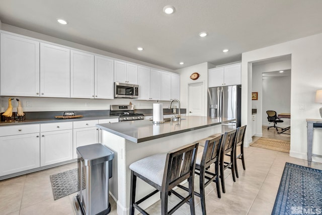 103 Pilot Peak, Carson City, NV 89701 - kitchen featuring stainless steel appliances, dark countertops, a kitchen breakfast bar, white cabinets, and light tile patterned floors