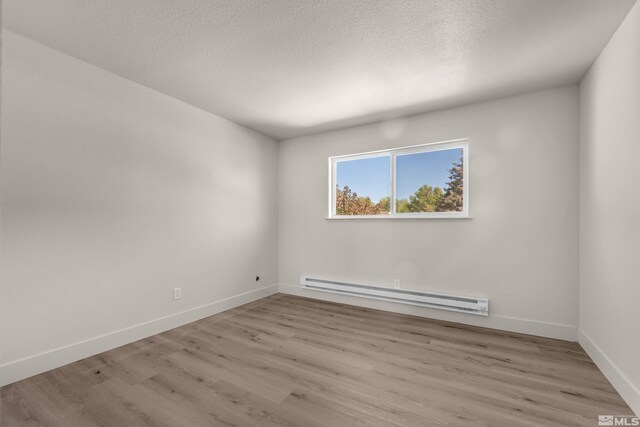 745 Jamaica Ave Unit 4, Reno, NV 89502 - spare room featuring baseboard heating, light wood-style flooring, baseboards, and a textured ceiling