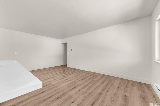 745 Jamaica Ave Unit 4, Reno, NV 89502 - unfurnished living room featuring light wood-style flooring, baseboards, and a baseboard radiator