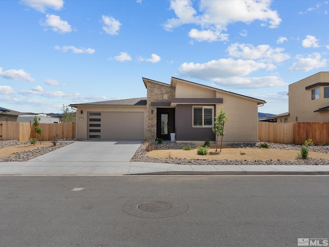 view of front facade featuring a garage, concrete driveway, and fence