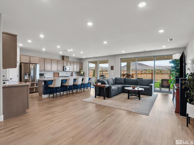 living room with plenty of natural light, light wood finished floors, and recessed lighting