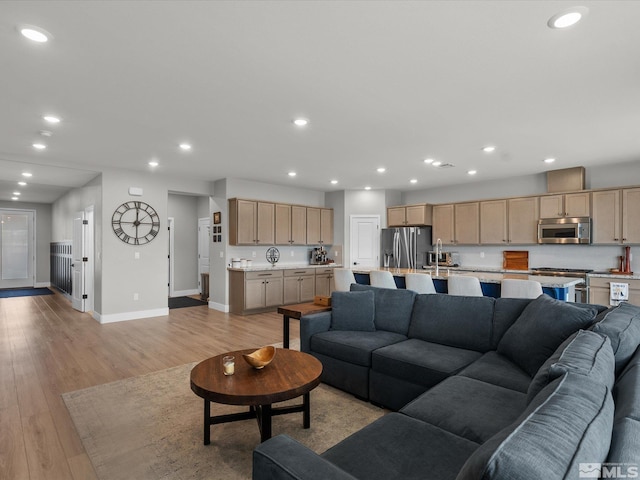 living room featuring baseboards, recessed lighting, and light wood-style floors