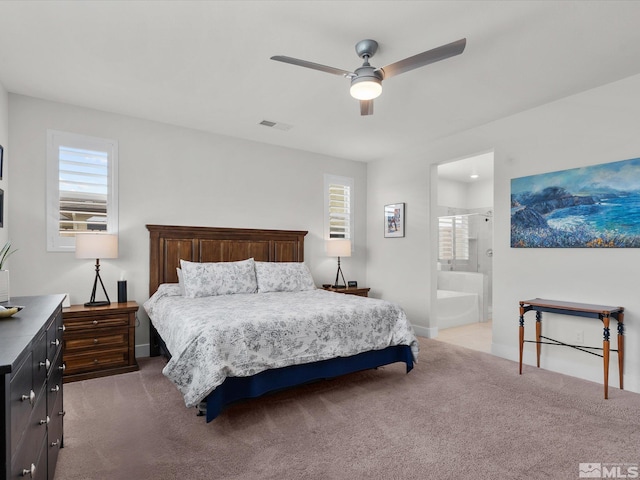 carpeted bedroom featuring a ceiling fan, ensuite bath, and baseboards