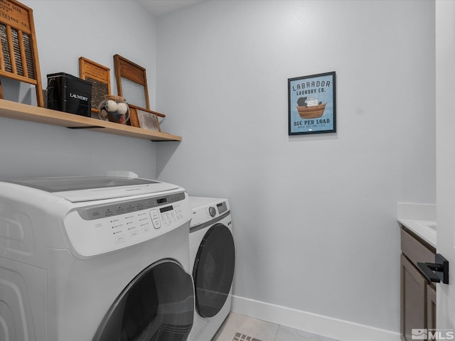 clothes washing area with washing machine and clothes dryer, baseboards, and light tile patterned floors