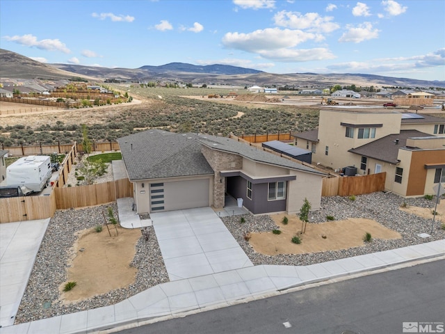 view of front of property with a mountain view, driveway, a garage, and fence