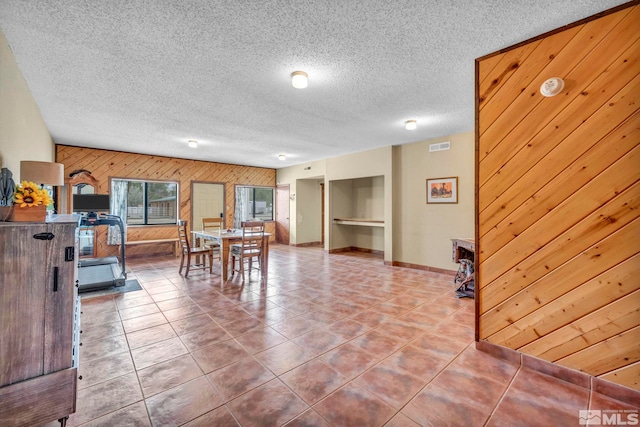1131 Linda Anne Ct, Gardnerville, NV 89410 - tiled dining area with wooden walls, baseboards, an accent wall, and a textured ceiling