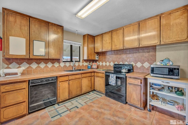 1131 Linda Anne Ct, Gardnerville, NV 89410 - kitchen featuring black appliances, tile counters, a sink, tasteful backsplash, and brown cabinetry