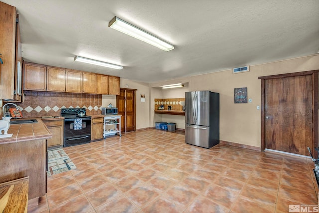 1131 Linda Anne Ct, Gardnerville, NV 89410 - kitchen with stainless steel appliances, a sink, tile countertops, backsplash, and a textured ceiling