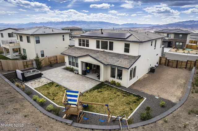5410 Cactus Quartz Ct, Sparks, NV 89436 - back of property with a mountain view, a patio, stucco siding, roof mounted solar panels, and a fenced backyard
