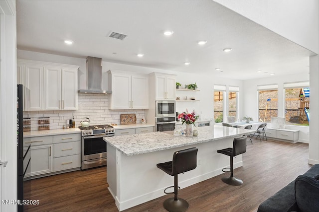 5410 Cactus Quartz Ct, Sparks, NV 89436 - kitchen with stainless steel appliances, wall chimney range hood, a kitchen island, a breakfast bar, and tasteful backsplash