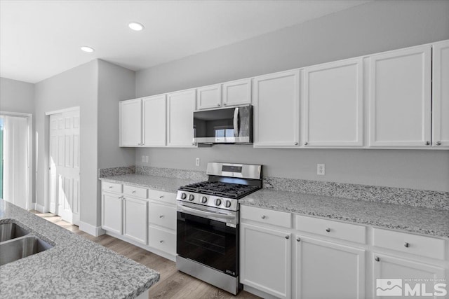 8952 Mahon Dr, Reno, NV 89506 - kitchen with stainless steel appliances, white cabinets, light wood-type flooring, recessed lighting, and light stone counters