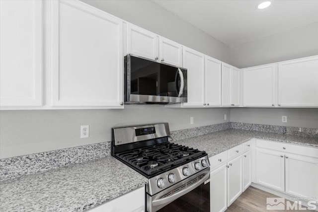 8952 Mahon Dr, Reno, NV 89506 - kitchen with stainless steel appliances, white cabinets, recessed lighting, light stone counters, and light wood-style flooring