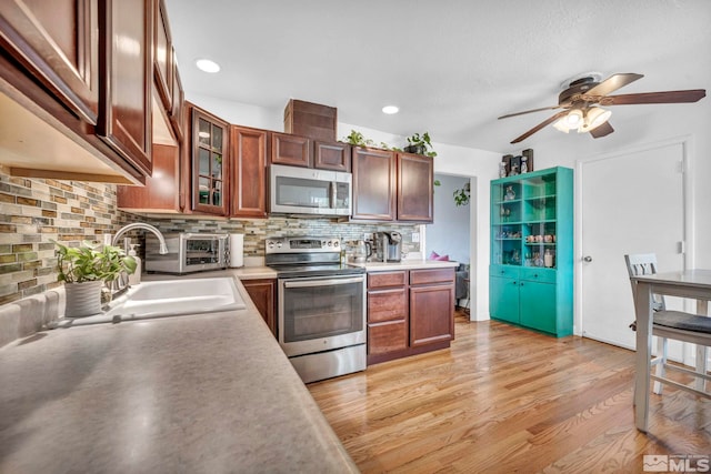 20 E Devere Way, Sparks, NV 89431 - kitchen with appliances with stainless steel finishes, a ceiling fan, backsplash, light wood-type flooring, and glass insert cabinets