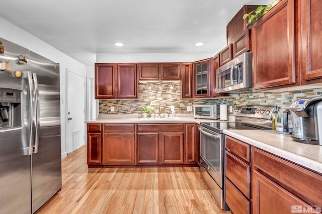 20 E Devere Way, Sparks, NV 89431 - kitchen with stainless steel appliances, a sink, light countertops, light wood-style flooring, and tasteful backsplash