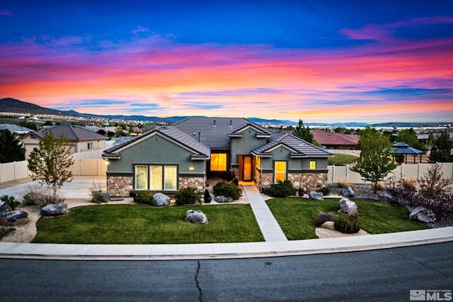 view of front of home with stone siding, a tile roof, a mountain view, stucco siding, and driveway