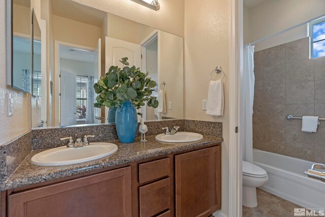 bathroom with toilet, shower / bath combo, healthy amount of natural light, and double vanity