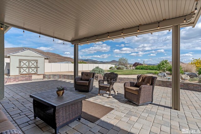 view of patio / terrace with a shed, an outdoor structure, fence, an outdoor hangout area, and a mountain view