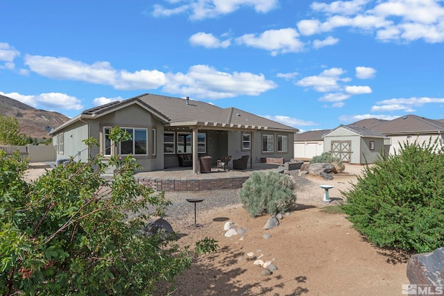 back of house featuring a shed, an outdoor structure, stucco siding, a patio, and fence