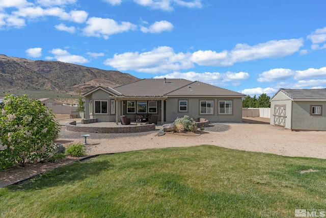 back of property with a patio area, an outbuilding, a storage shed, a mountain view, and stucco siding