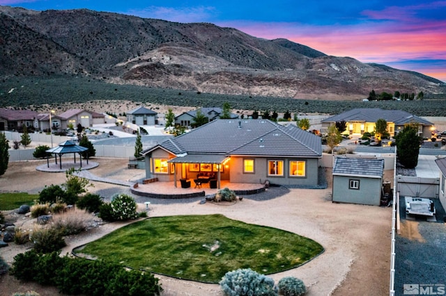back of house at dusk featuring a gazebo, fence, a mountain view, and a patio