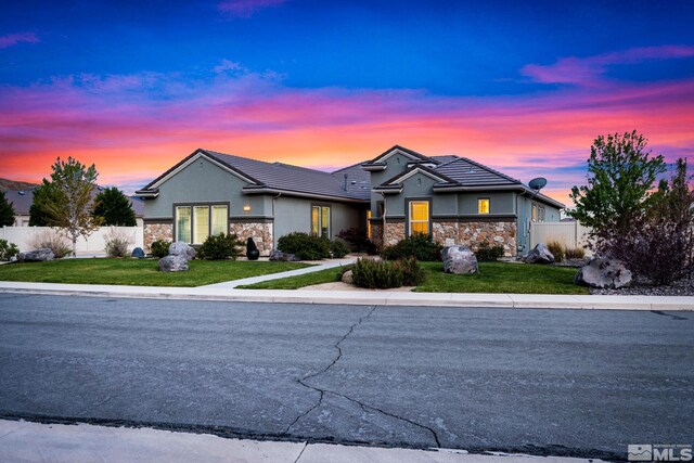 ranch-style house with stone siding, stucco siding, and a tile roof