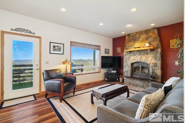 living room featuring wood finished floors, recessed lighting, and a stone fireplace