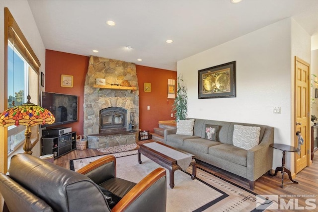 living area with wood finished floors, recessed lighting, and a stone fireplace