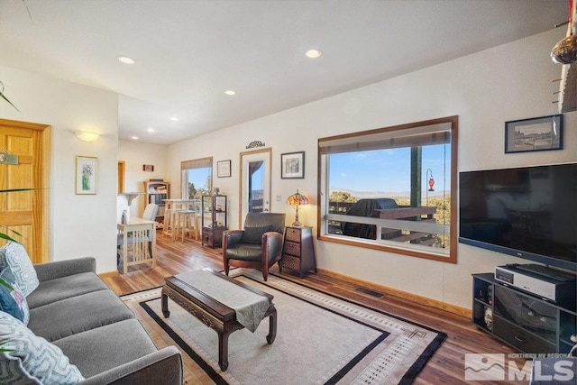 living area with wood finished floors, plenty of natural light, and recessed lighting