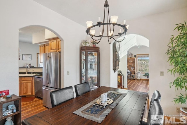 dining room with arched walkways, wood finished floors, and a chandelier