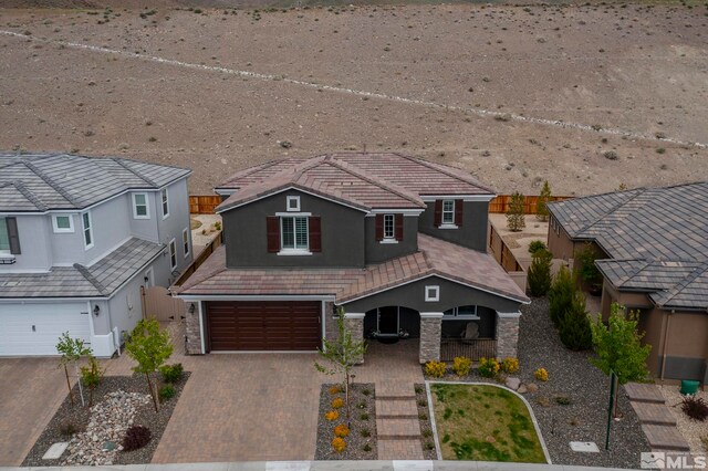3325 Show Jumper Ln, Reno, NV 89521 - view of front facade with stucco siding, a garage, covered porch, decorative driveway, and a tiled roof