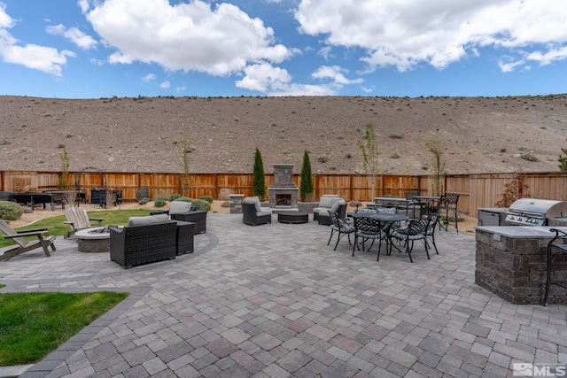 3325 Show Jumper Ln, Reno, NV 89521 - view of patio / terrace with a grill, fence, outdoor dining area, an outdoor living space with a fireplace, and a mountain view
