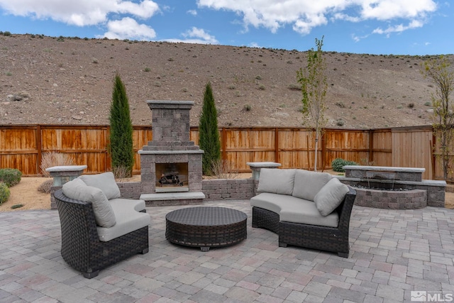 3325 Show Jumper Ln, Reno, NV 89521 - view of patio / terrace featuring a mountain view, a fenced backyard, and an outdoor living space with a fireplace